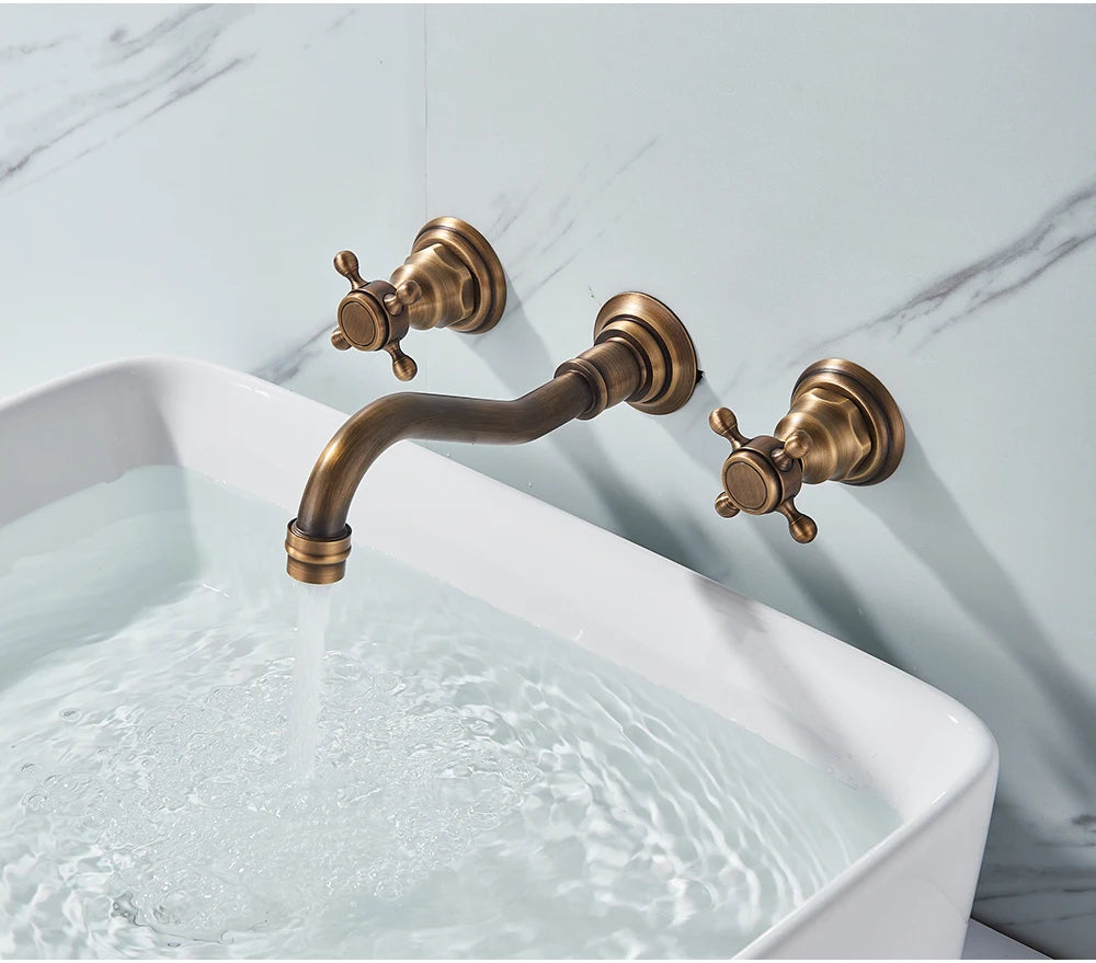 Antique brass three-piece wall-mount faucet filling a white rectangular basin with water