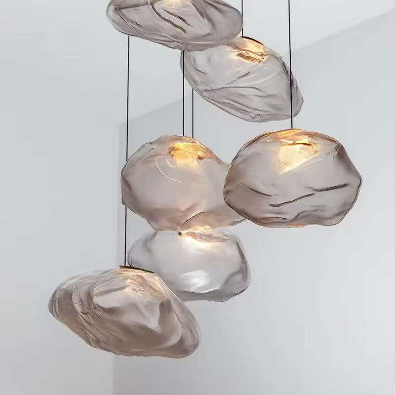 Cluster of clear cloud-shaped blown glass pendant lights glowing against a white wall