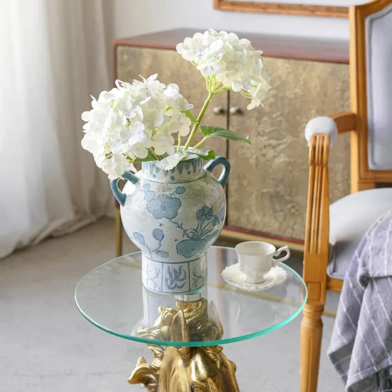 Blue and white amphora vase with white hydrangeas on a glass side table