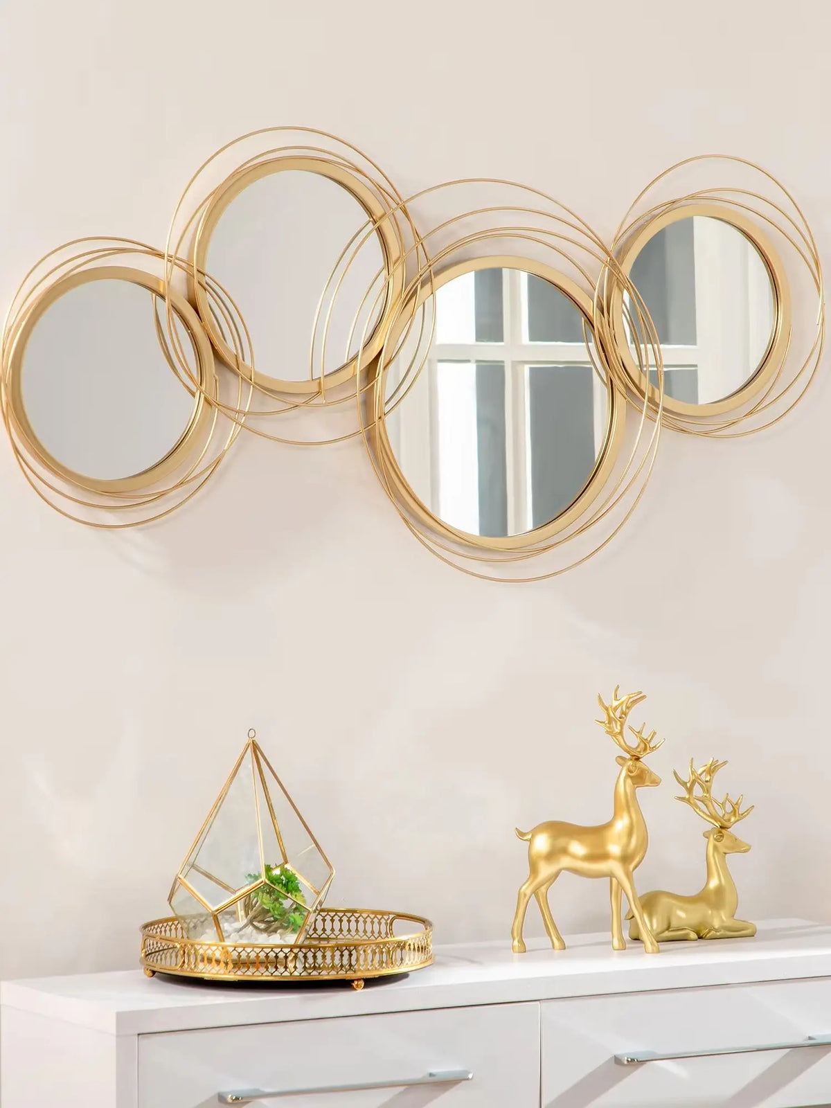 Gold ring wall mirror with four round mirrors in overlapping gold metal rings, hung on a wall