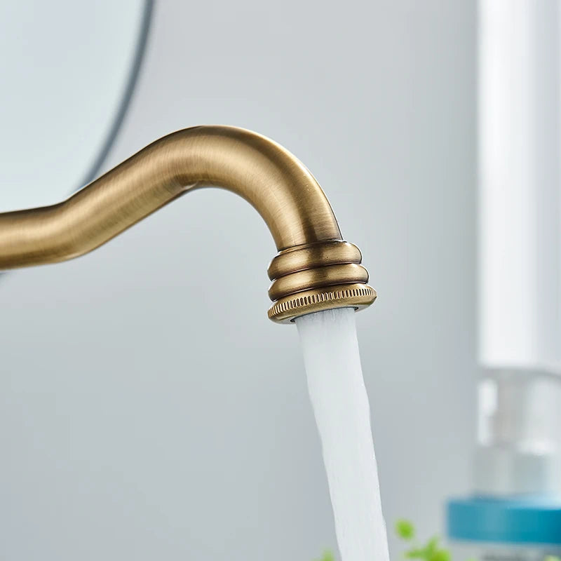 Close-up of the antique brass faucet spout with ringed aerator and running water