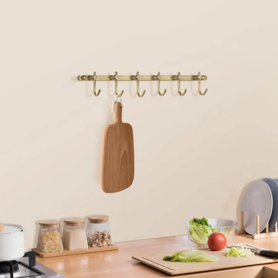Brushed brass towel rail with six curved hooks (mounted in a kitchen)