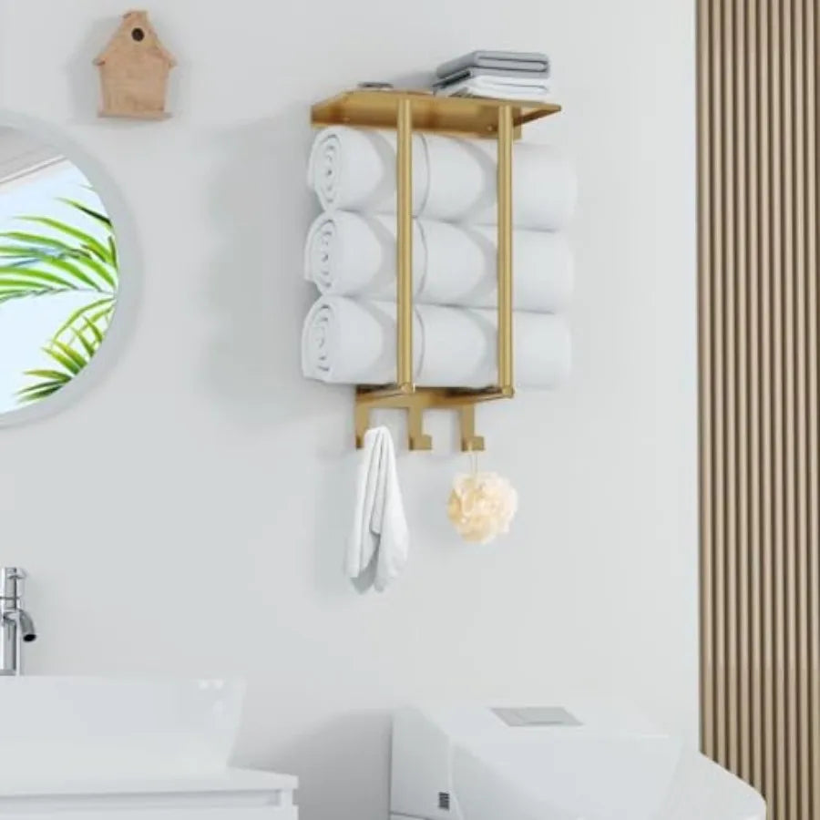Brushed gold wall towel rack with a top shelf, rolled towels and three hooks (in a bathroom)