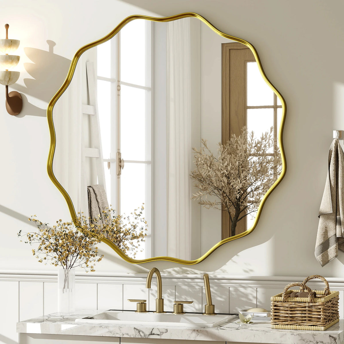 Gold wavy scalloped mirror above a marble vanity with brass faucet and sconce