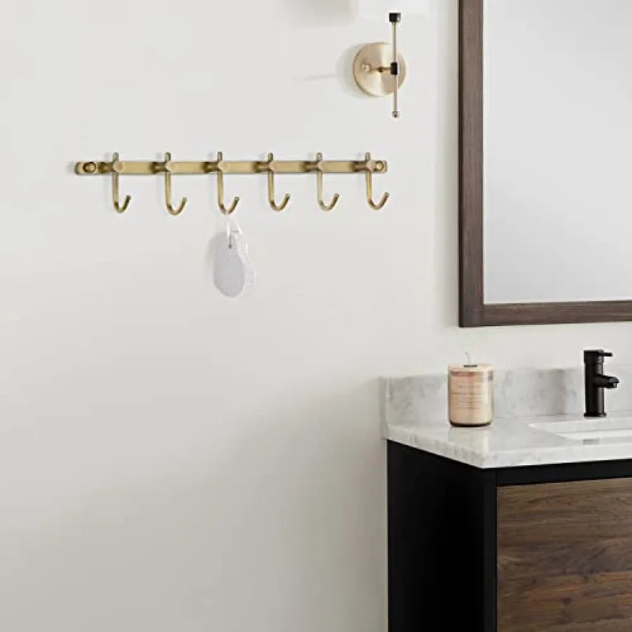 Brushed brass towel rail with six curved hooks (mounted in a bathroom)