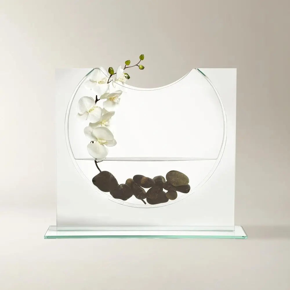 Clear glass ellipse vase with a white orchid and black stones