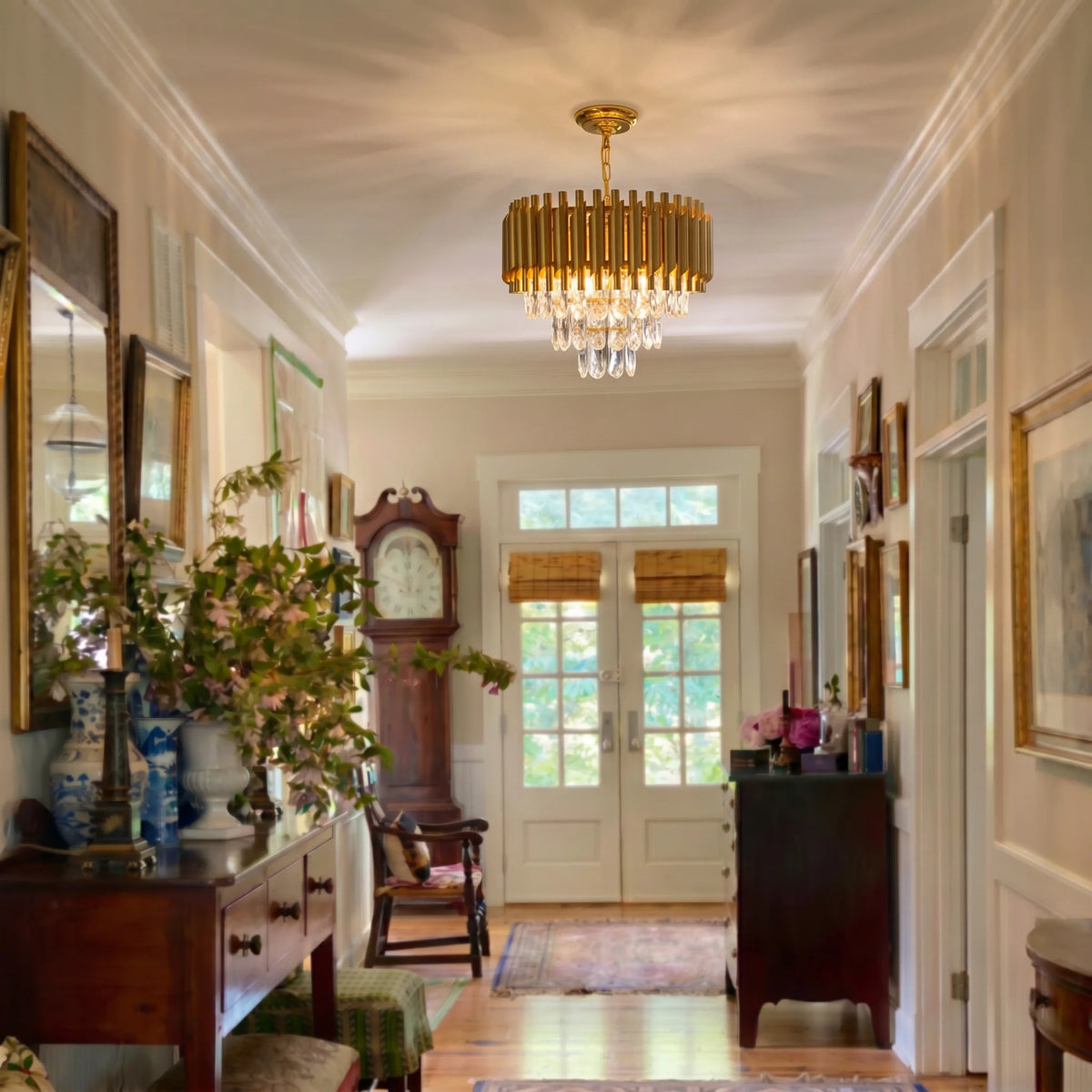Gold fluted K9 crystal chandelier hanging in a long entry hallway with French doors