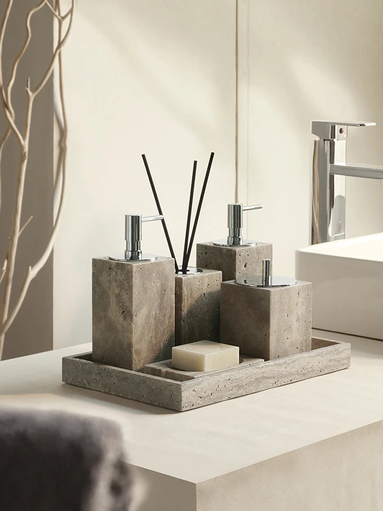 Gray travertine bathroom accessories set with silver-tone pumps, reed diffuser and soap on tray