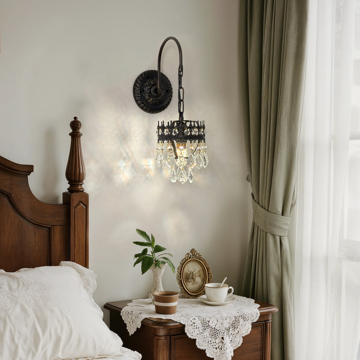 Crystal shade wall sconce on a black iron arm lighting a bedside nightstand
