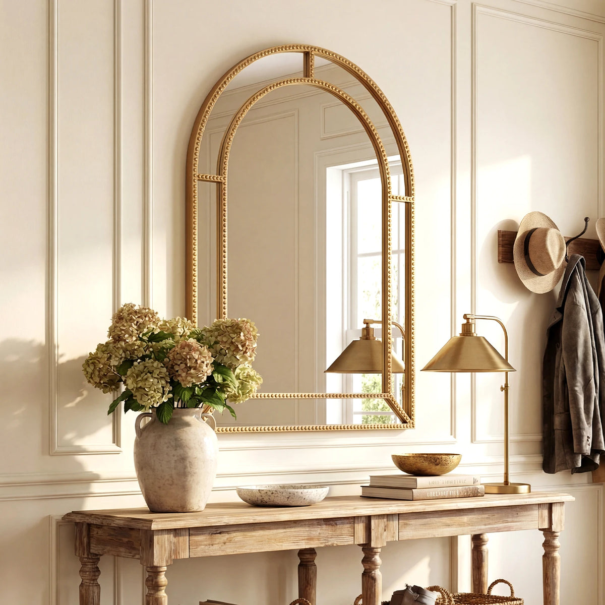 Gold beaded arched wall mirror above an entryway console table