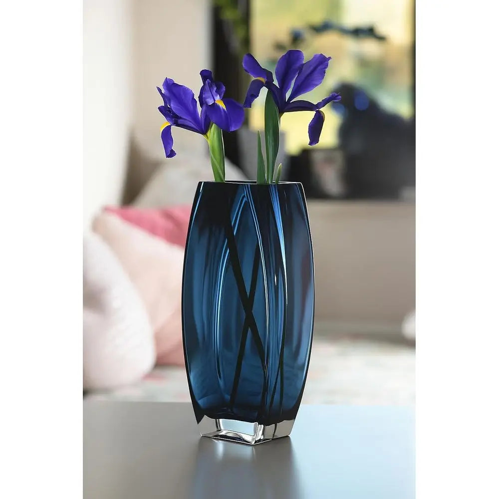 Blue-teal art glass vase with purple irises on a side table