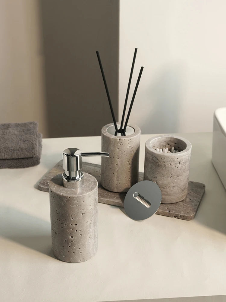 Gray travertine dispenser, reed diffuser and lidded canister with lid off on a tray