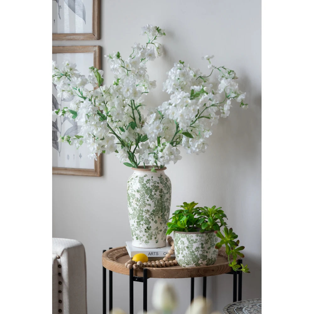 White and green floral ceramic vase with white blooms on a side table