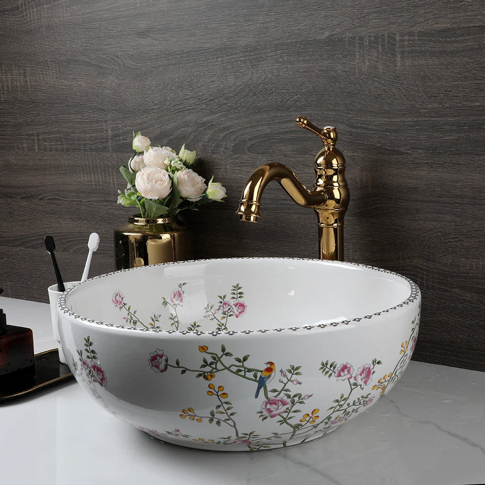 Flower-and-bird porcelain vessel sink on a white counter with gold faucet