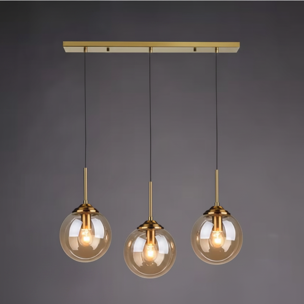 Three amber glass globe pendants on a brass linear canopy