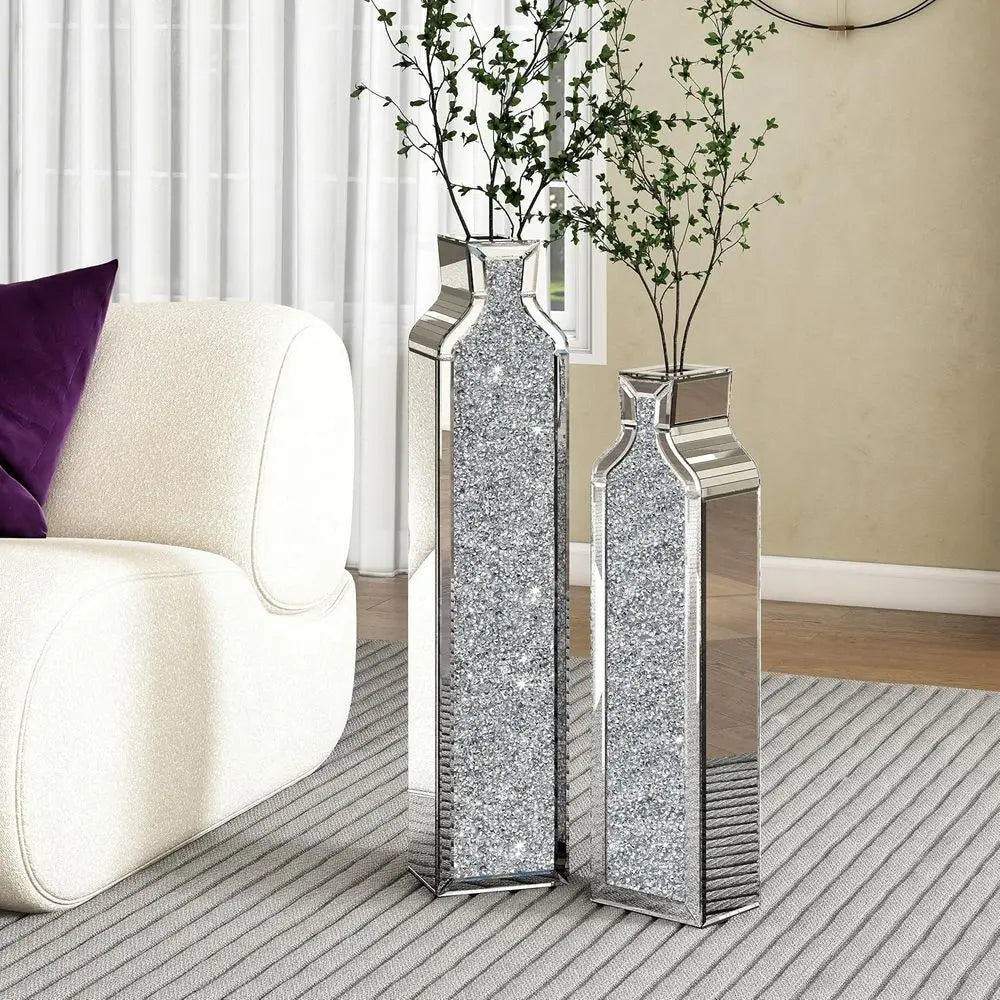 Pair of tall mirrored floor vases with branches beside a white armchair