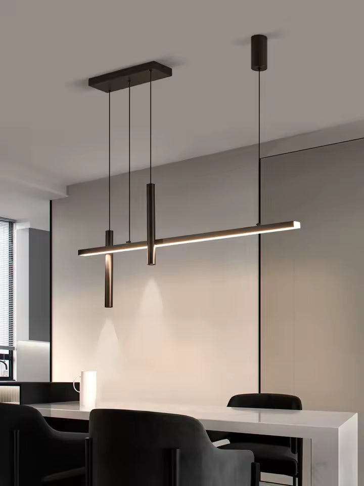 Black linear LED pendant light hanging over a white island with dining chairs
