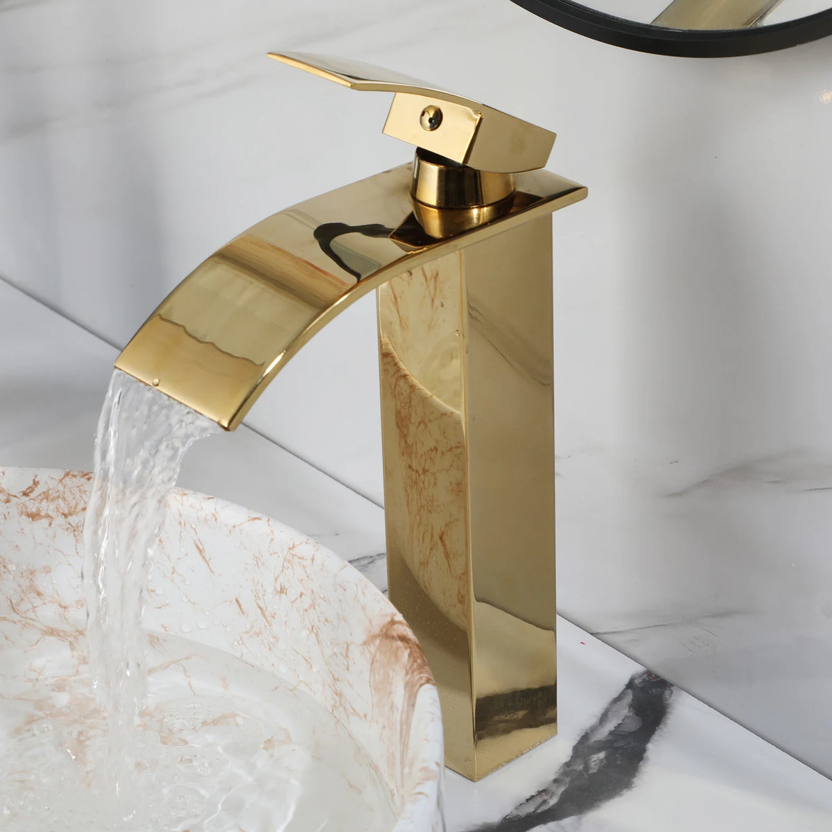 White marble-look round vessel sink with gold faucet on a marble counter
