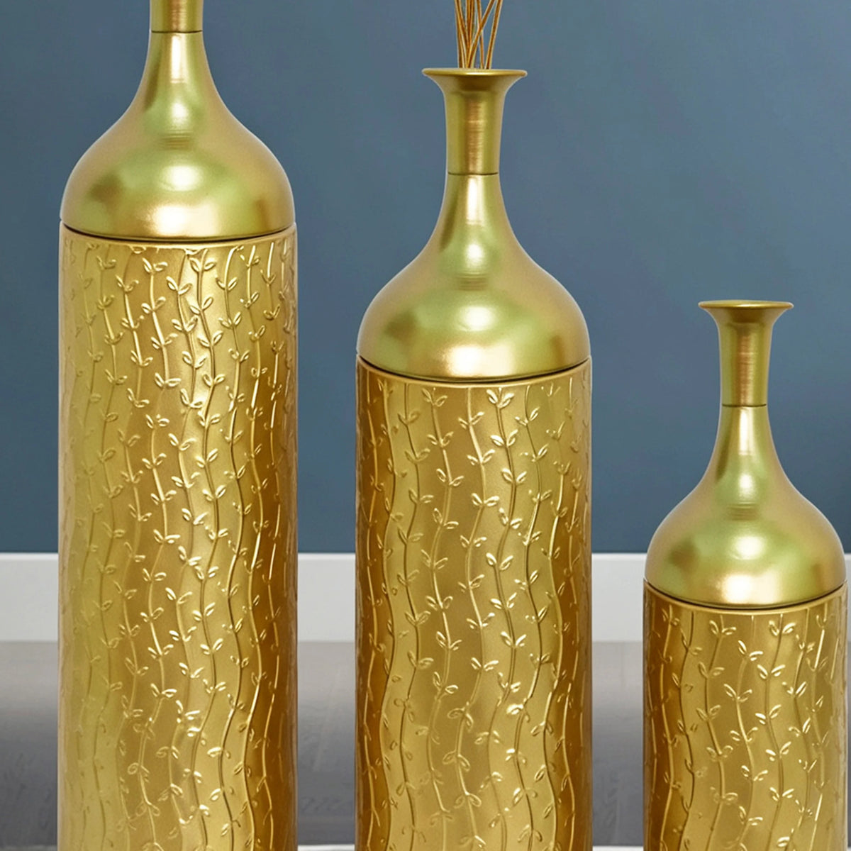 Close-up of the embossed leaf pattern on gold metal vases