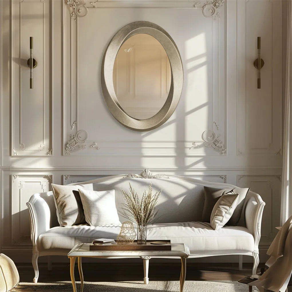 Oval champagne-finish mirror hung above a sofa in a paneled living room
