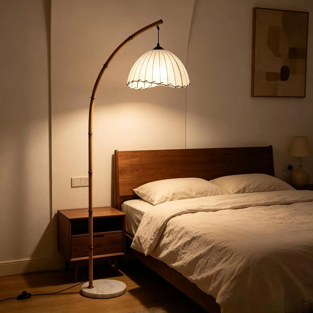 Bamboo arc floor lamp with pleated shade beside a bed