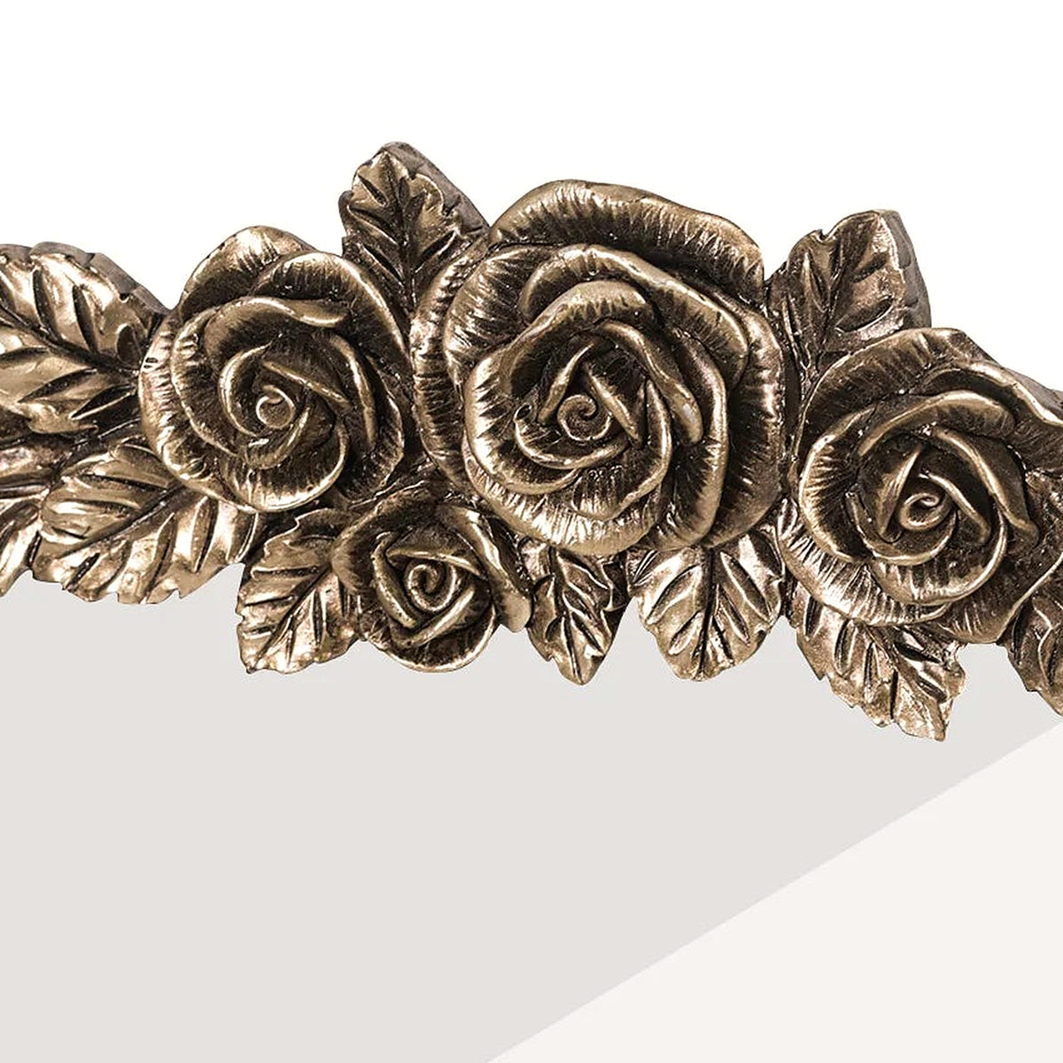 Close-up of the sculpted rose and leaf crest in aged antique brass on the arched mirror