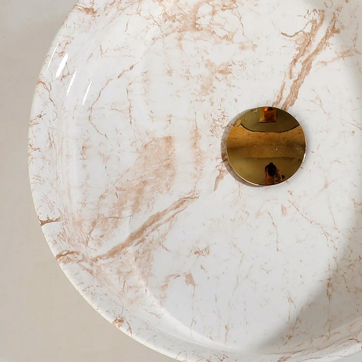 Detail of the curved ceramic rim and warm marble-look glaze on the vessel sink