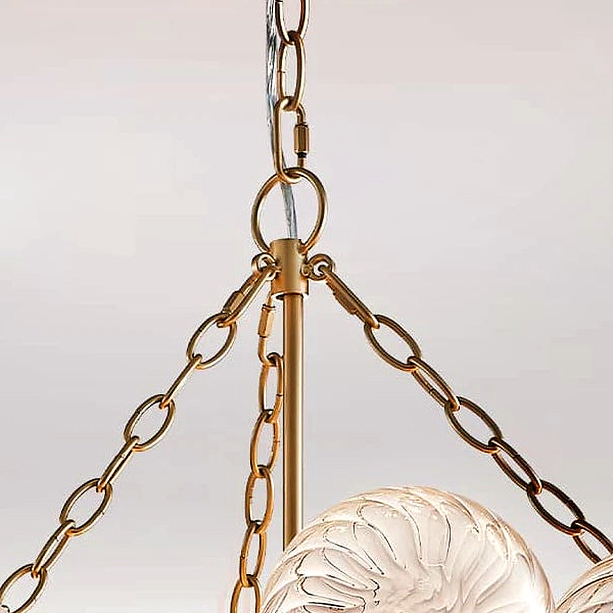 Detail of the brushed gold chains and central stem above the glass bubble cluster