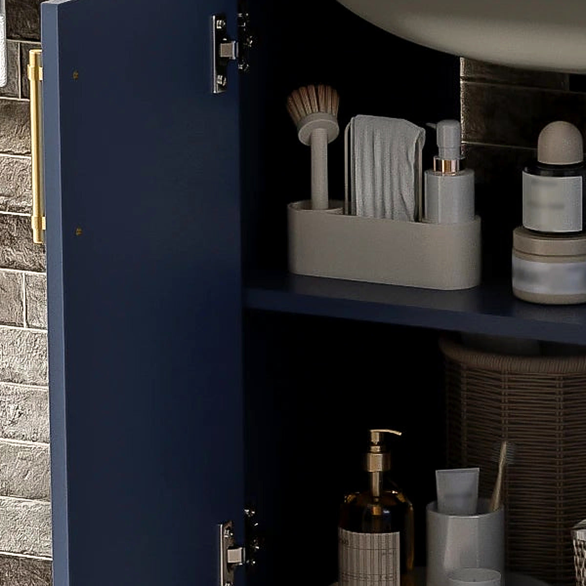 Detail of the open navy cabinet door, hinge and satin gold pull (toiletries shown for styling)