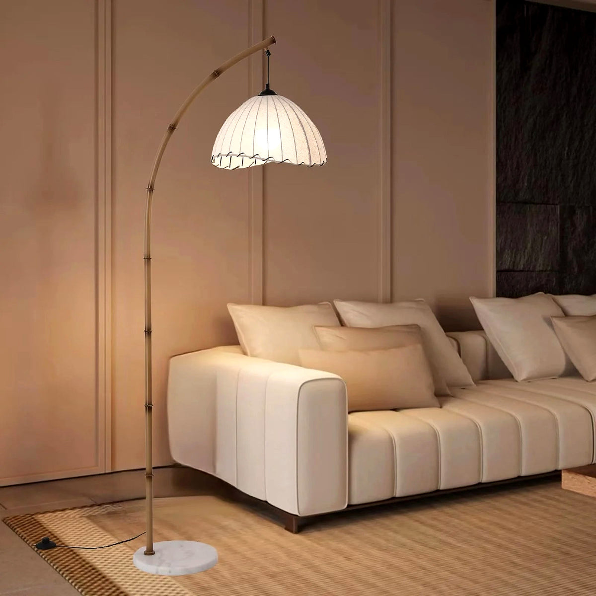 Bamboo arc floor lamp with pleated shade and marble base beside a cream sofa (furniture and décor shown for styling)