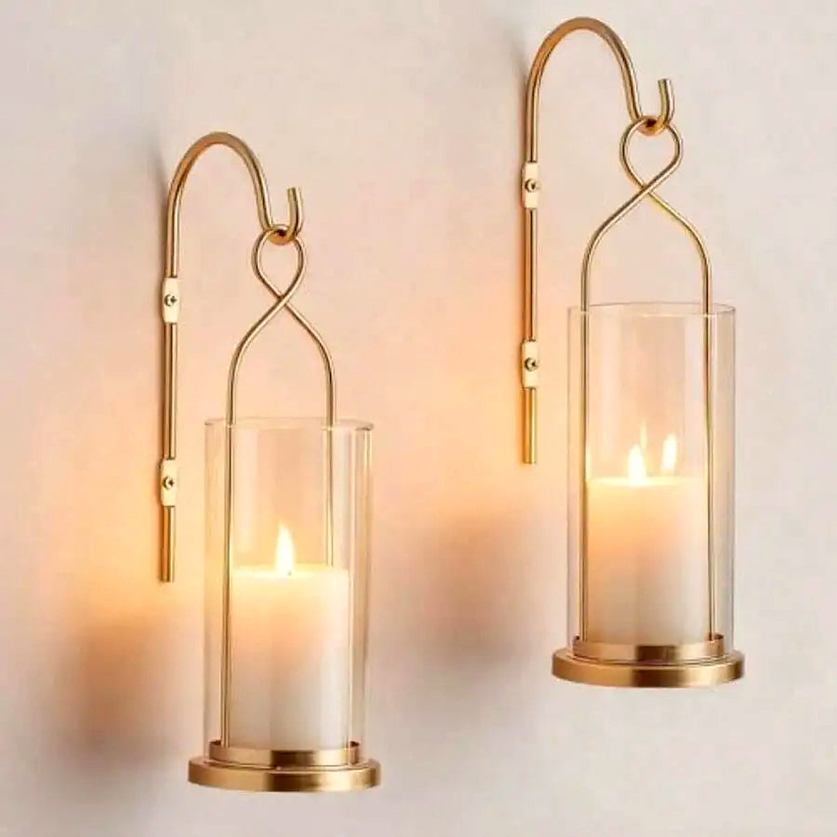 Pair of gold hurricane candle wall sconces with clear glass shades glowing with pillar candles (candles not included)