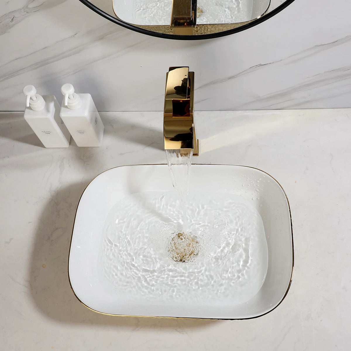 Polished gold waterfall faucet pouring into the hammered gold ceramic vessel sink