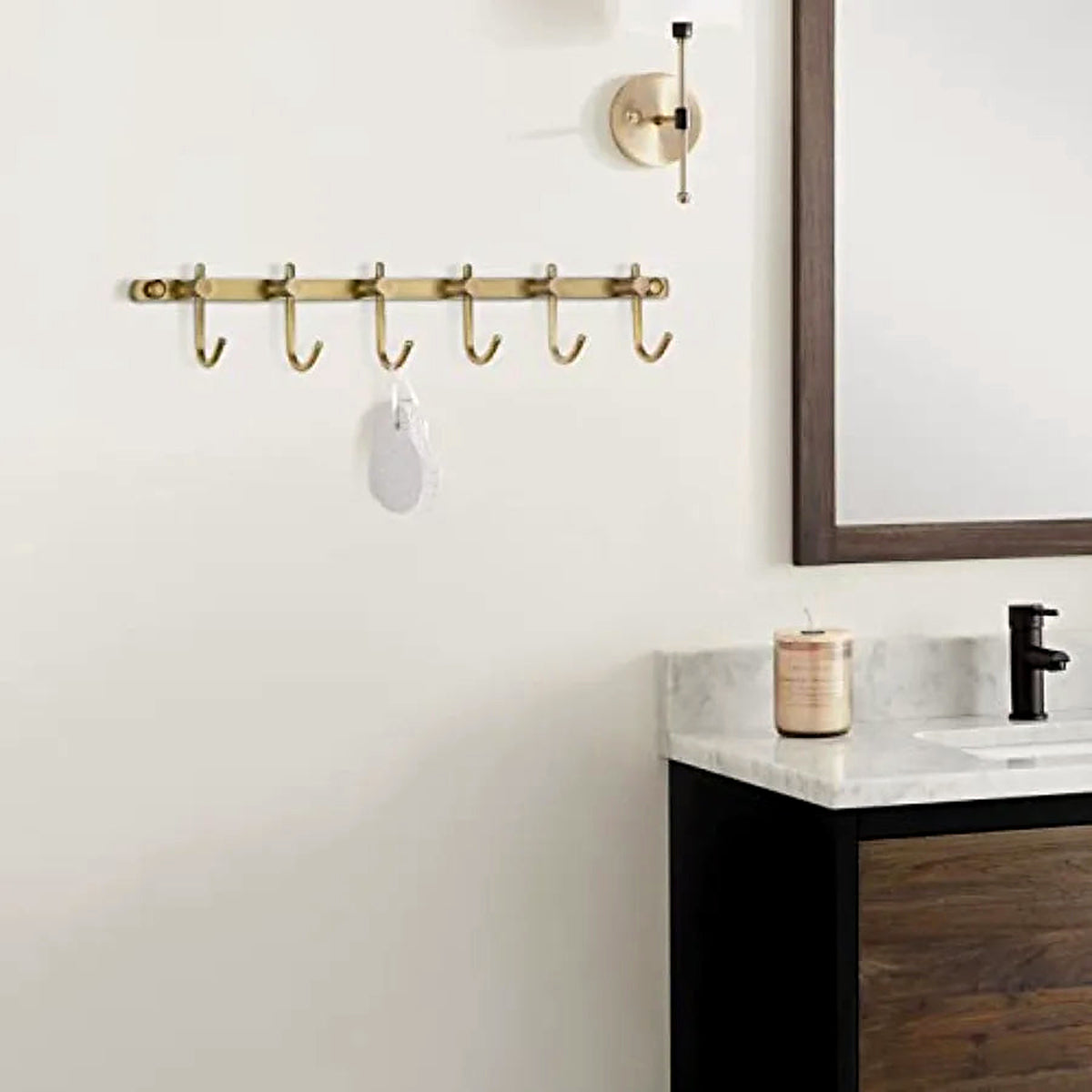 Brushed brass six-hook towel rail mounted above a bathroom vanity (vanity and décor shown for styling)