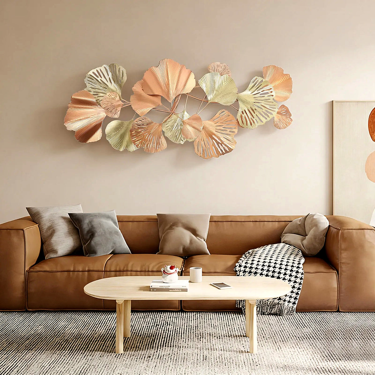 54 x 24 in ginkgo leaf metal wall sculpture hung horizontally above a cognac leather sofa