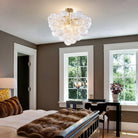 Ribbed glass globe cluster chandelier mounted semi-flush above a bedroom with tall windows
