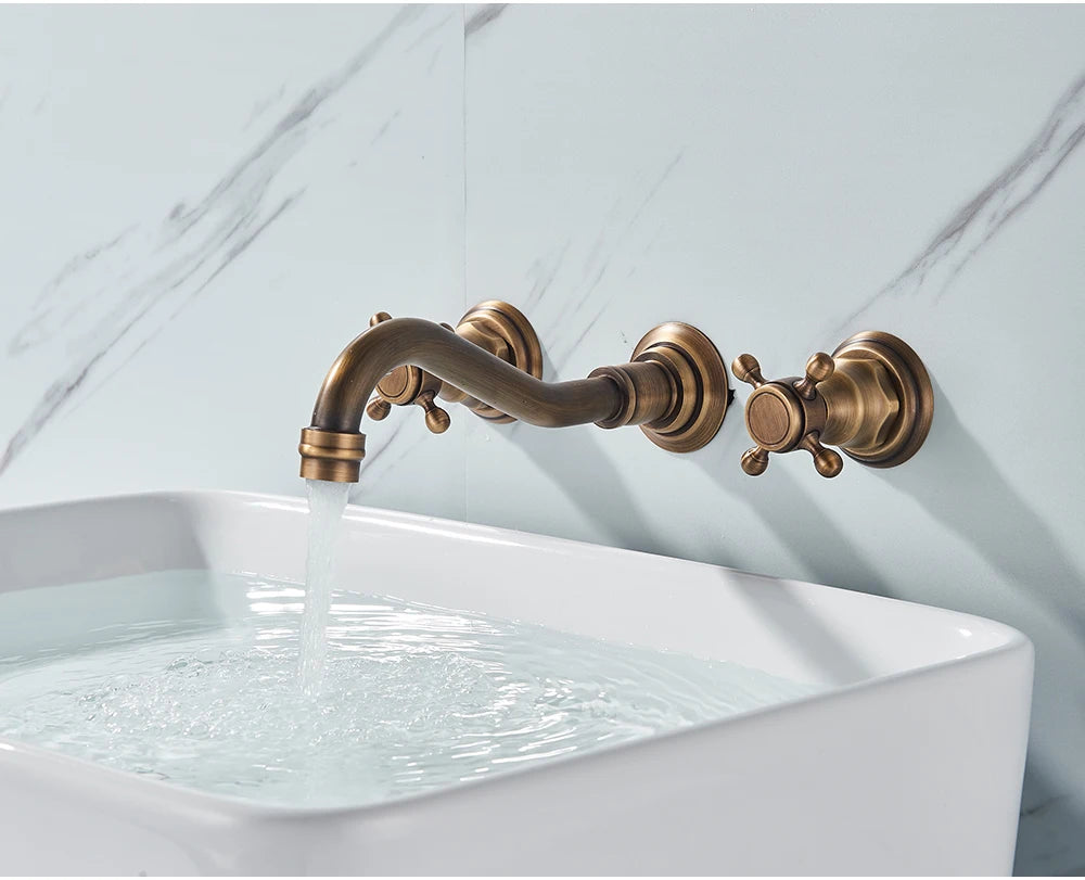 Side angle of the antique brass wall-mount faucet running water into a white sink