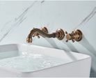 Side angle of the antique brass wall-mount faucet running water into a white sink