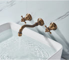Antique brass three-piece wall-mount faucet filling a white rectangular basin with water