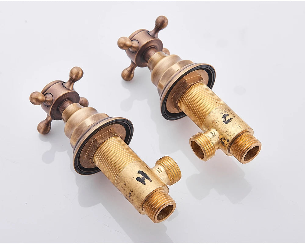 Antique brass wall-mount faucet cross-handle valves shown with their brass rough-in bodies