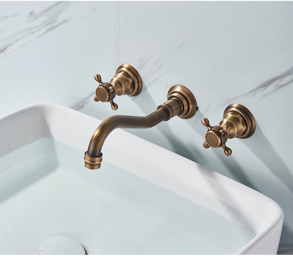 Antique brass wall-mount bathroom faucet with cross handles above a white vessel sink