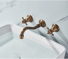Antique brass wall-mount bathroom faucet with cross handles above a white vessel sink