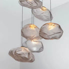 Cluster of clear cloud-shaped blown glass pendant lights glowing against a white wall