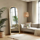 Arched rattan floor mirror in a living room with a gray sofa