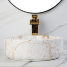 White marble-look ceramic vessel sink with tall gold faucet, side view