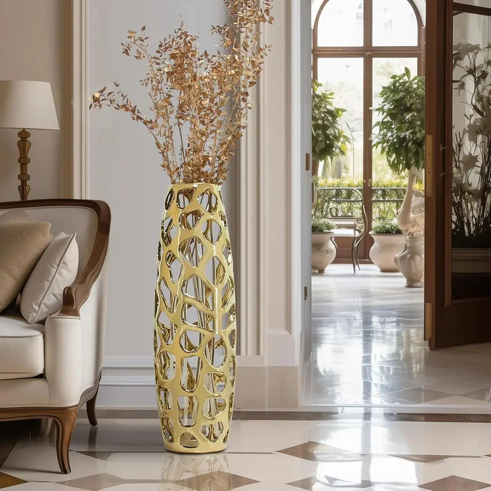Gold coral-like openwork vase with dried stems in a bright hallway