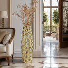 Gold coral-like openwork vase with dried stems in a bright hallway
