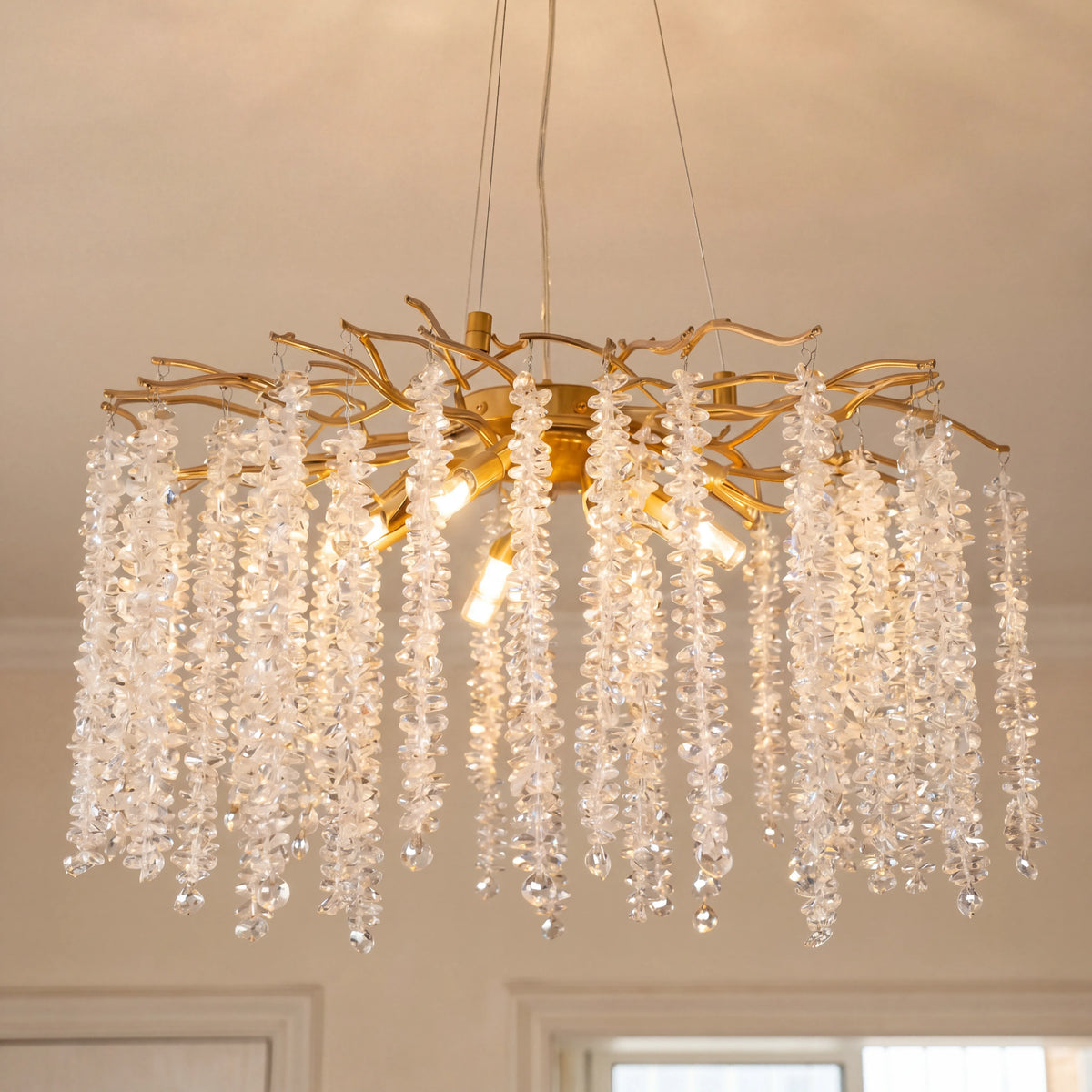 Close-up of the gold branch chandelier with cascading raindrop K9 crystal strands lit