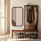 Octagon walnut wood wall mirror hung vertically beside an entryway coat rack and bench