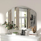 Arched Venetian glass mirror with beveled edge panels over a white mantel reflecting windows