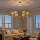 Six-Light Gold Chandelier with Rattan Shades, lit above a sofa in a coastal living room